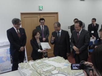 会場内に設置されているジオラマを見つめるスーツ姿の役員たちの写真