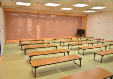 床面に畳が敷かれ、低めのテーブルが置かれている集会室の写真