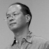 眼鏡にワイシャツ姿の樋渡啓佑氏のモノクロ写真