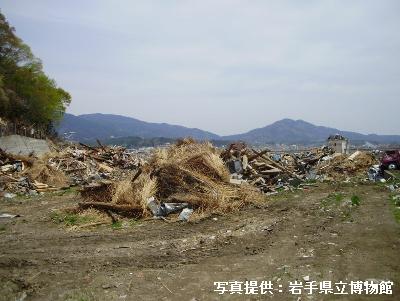 東北地方太平洋沖地震によって旧気仙小学校側付近まで流出した吉田家住宅の主屋の見るも無残にバラバラになった茅葺屋根部分の写真