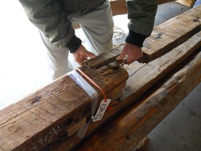 吉田家住宅の残存部材の切れ端同士を合わせ位置特定作業を中腰になりながらおこなう男性の手元のアップ写真