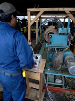 青い作業服の男性が機械を操作している写真