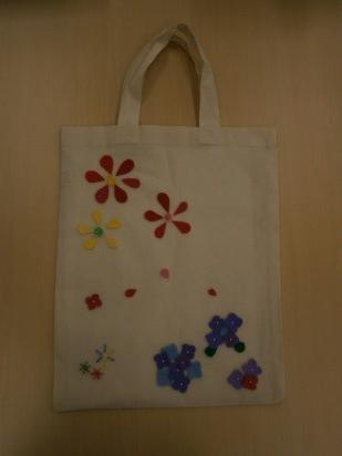 ビーズやフェルトなどで作った可愛いお花に彩られた図書館手芸教室で制作できる布製デコバッグの見本の写真