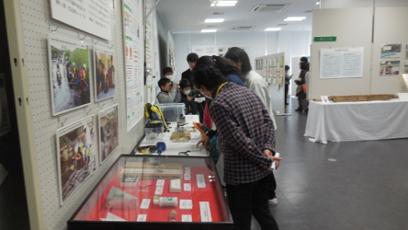 陸前高田市コミュニティホールの一室に展示された数々の文化財を興味深げに眺める来場者たちを左横から撮影した写真