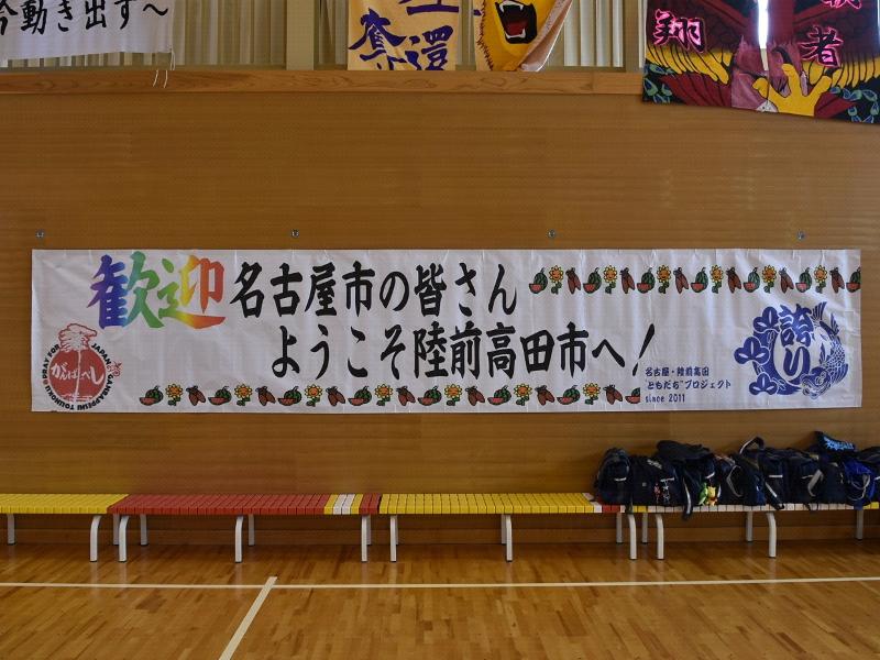 陸前高田市立第一中学校の体育館で壁に貼られた歓迎とカラフルな色で書かれ名古屋市の皆さんようこそ陸前高田市へと黒字で書かれた白色の横断幕の写真