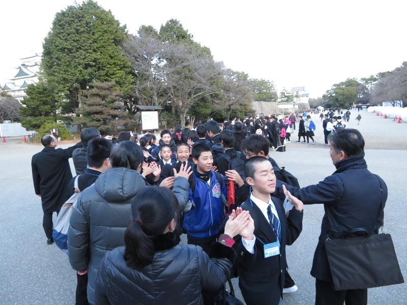 名古屋城内で両端で列になって真ん中を恥ずかしそうに通る男子中学生とハイタッチをする中学生らの写真