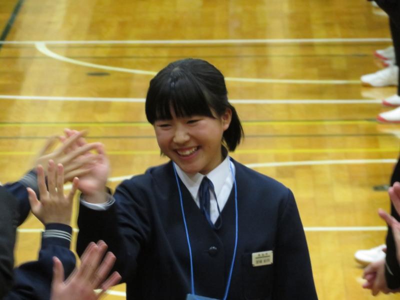 名古屋市内の中学校の体育館ではにかみながら迎えてくれる生徒たちとハイタッチをする陸前高田市の女子中学生の写真