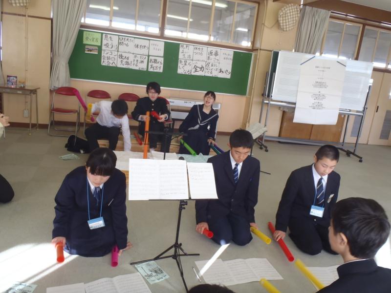 名古屋市内の中学校の教室で床置いた楽譜を確認しながらそれに合わせてカラフルな棒を動かす中学生たちの写真