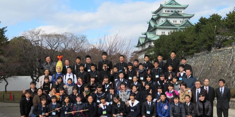 名古屋城をバックに縦5列で横に並ぶ陸前高田市と名古屋市の中学2年生の生徒および関係者らが記念撮影をする写真