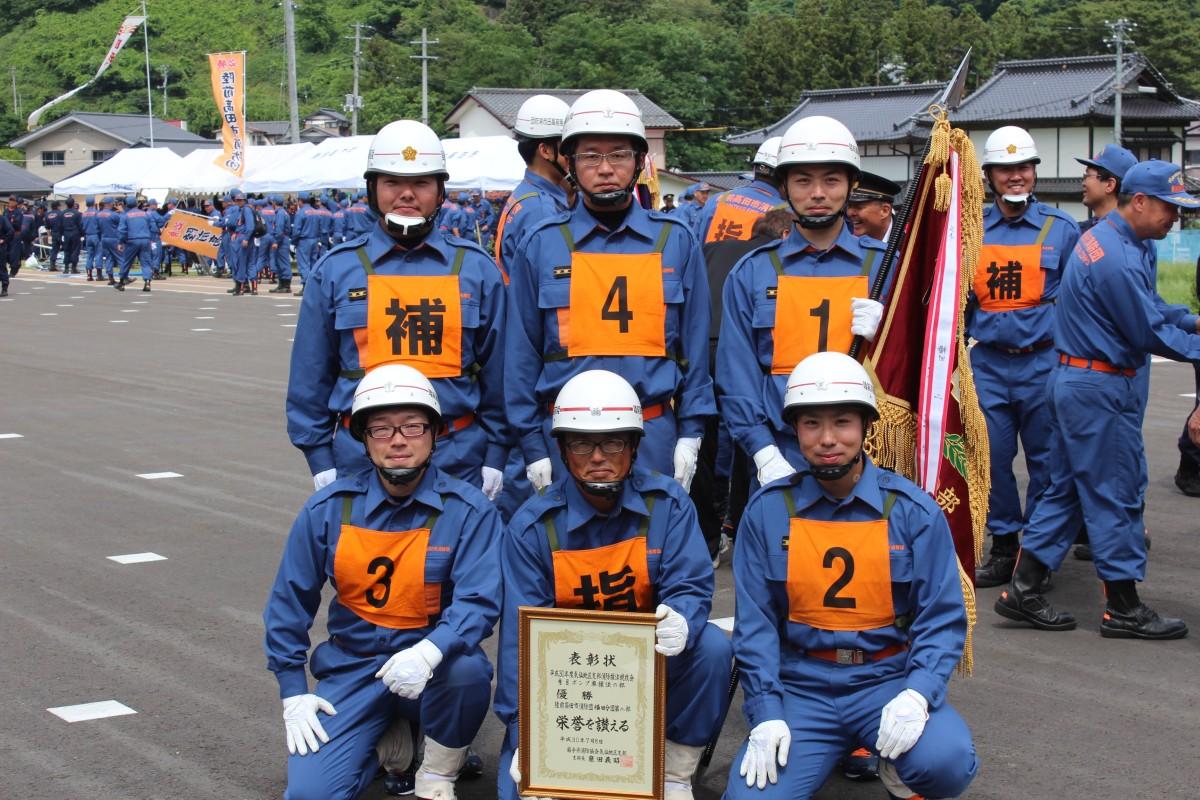 表彰状と旗を持ち記念撮影をしている横田分団第2部の団員達の写真