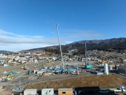 青空の下、背の高い重機が土台部分の作業をしている2020年1月の進捗状況の写真